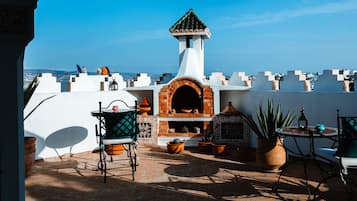 A rooftop patio with a brick oven, potted plants, and outdoor furniture.