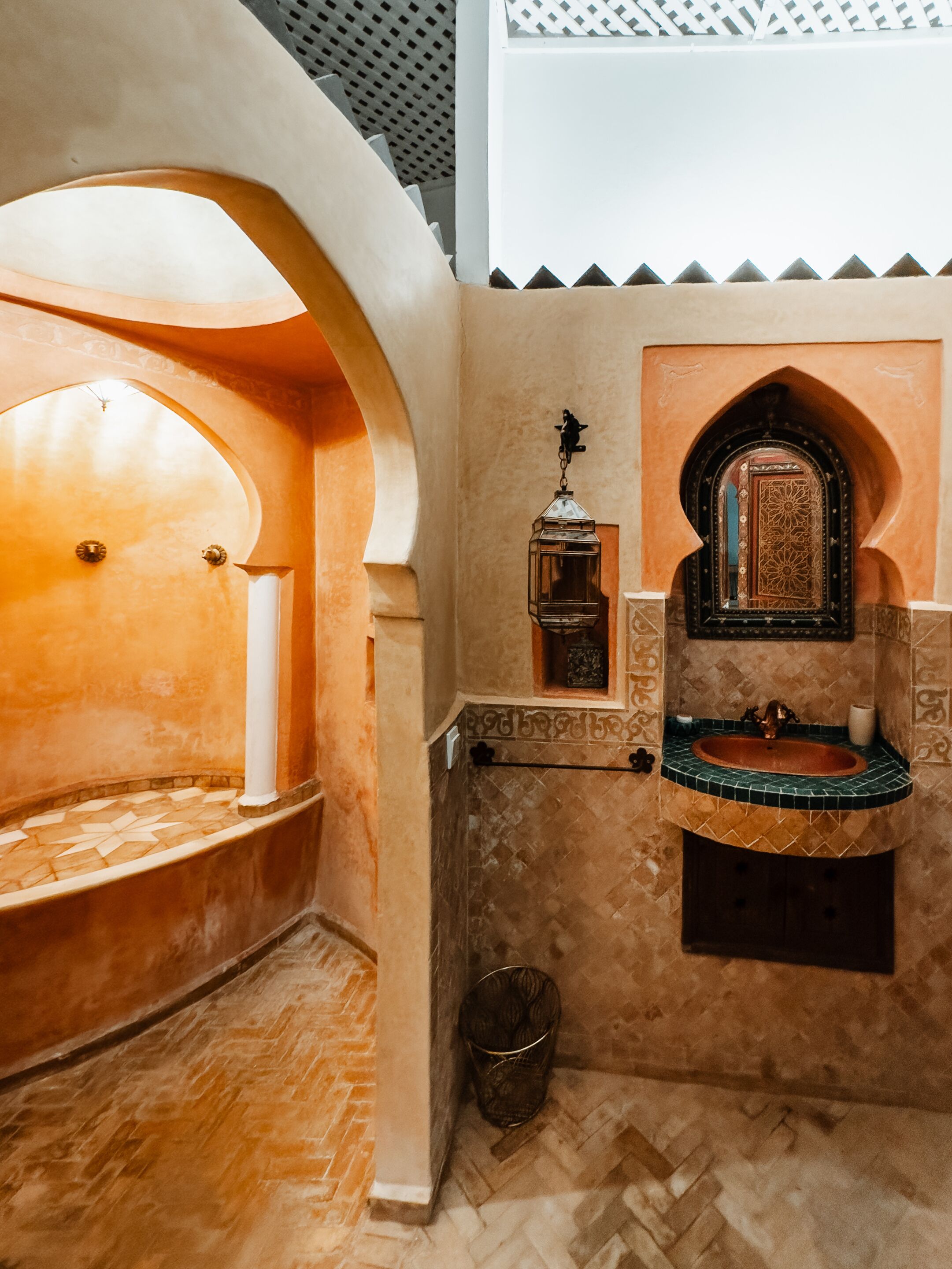 A traditional Moroccan interior with a tiled floor, a small sink, and a decorative lantern.