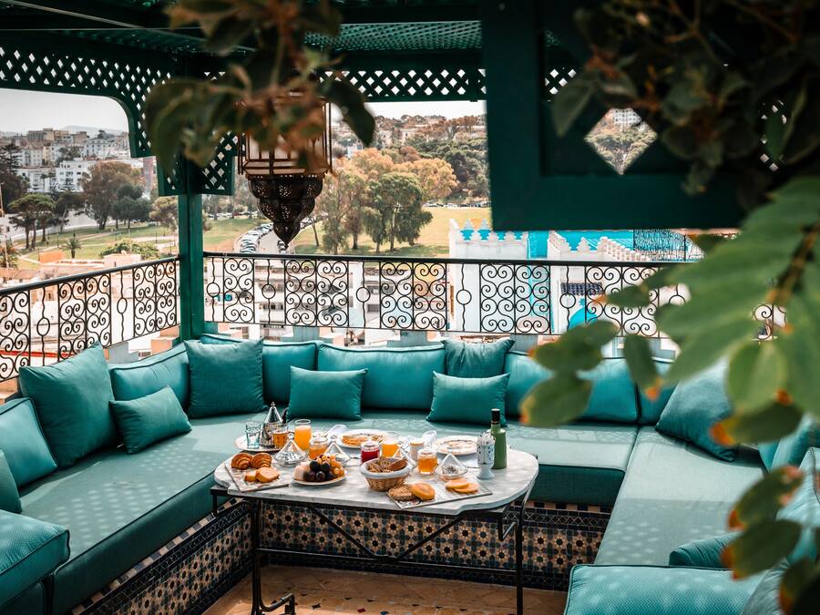 A balcony with a sofa, table with food, and a view of a cityscape.