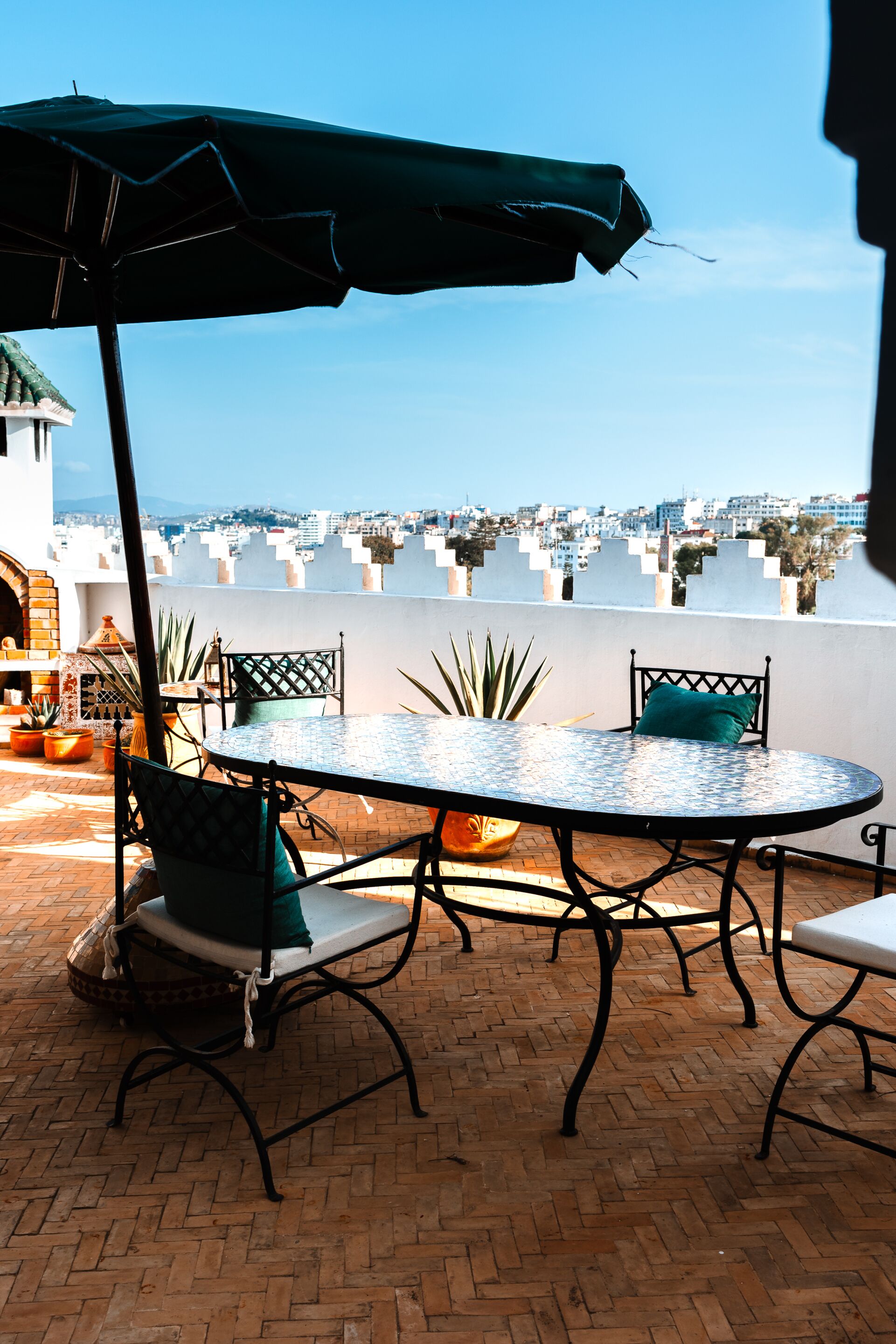A rooftop terrace with a round table, chairs, and an umbrella.