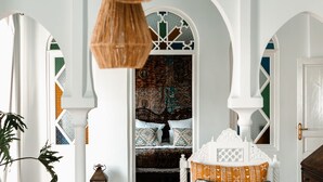 A room with a white chair, a patterned rug, and a decorative hanging light fixture. - Lalla Soulika (Tangier)