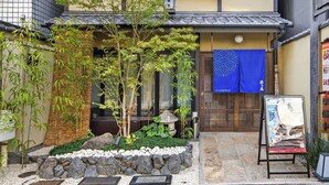 A traditional Japanese building with a tiled roof, a stone pathway, and a bamboo garden. - Hotel Rakurakuan (Kyoto)