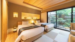 A hotel room with two beds, a sitting area, a view of greenery, and a traditional Japanese sliding door. - Hotel Rakurakuan (Kyoto)