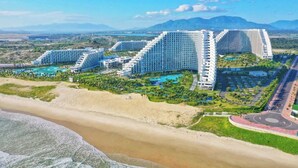 A coastal hotel with multiple high-rise buildings, a beach, and a large swimming pool complex. - THE ARENA CAM RANH (Bac Cam Ranh)