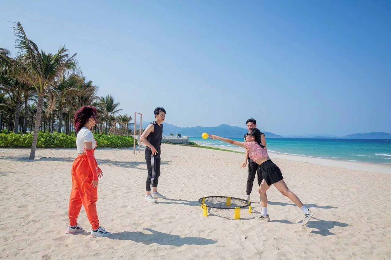 A beach scene with people playing with a ball and a trampoline.