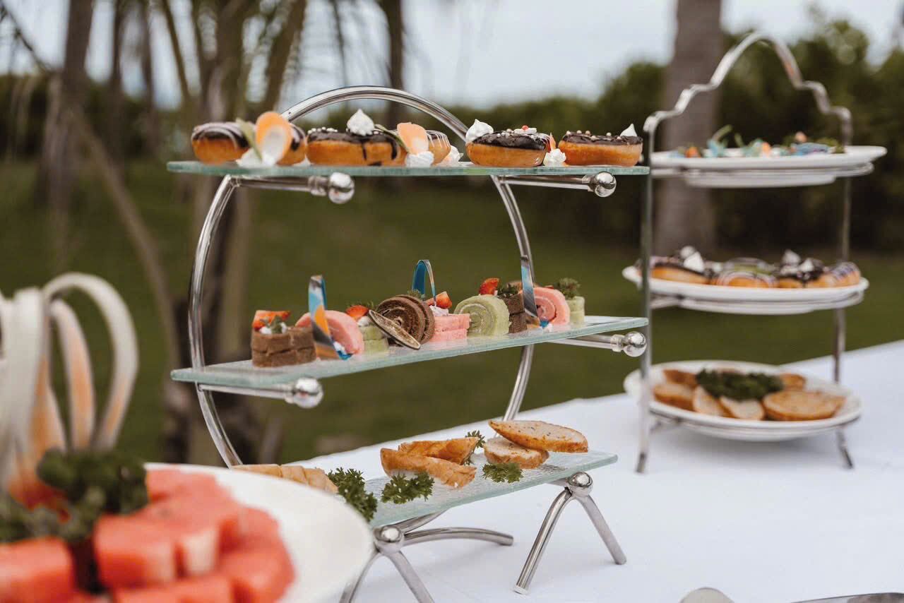A dessert display with various pastries and fruits on a glass stand.