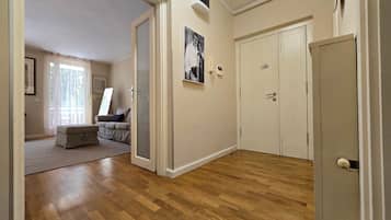 Una stanza con pavimento in legno, un divano, una porta e un quadro appeso al muro.