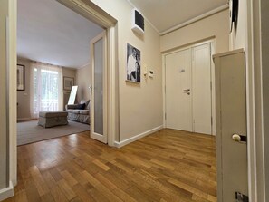 Una stanza con pavimento in legno, un divano, una porta e un quadro appeso al muro.