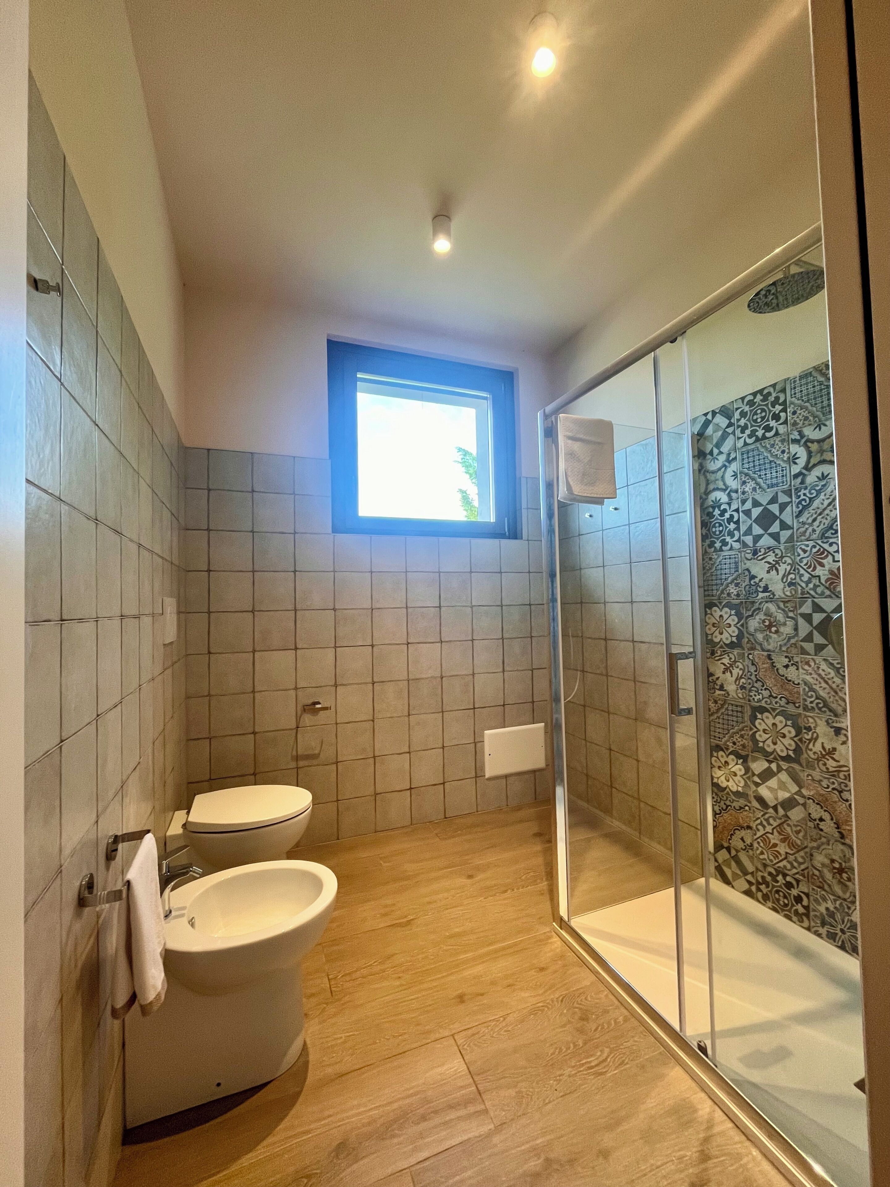 A bathroom with a toilet, bidet, and shower with a glass door.