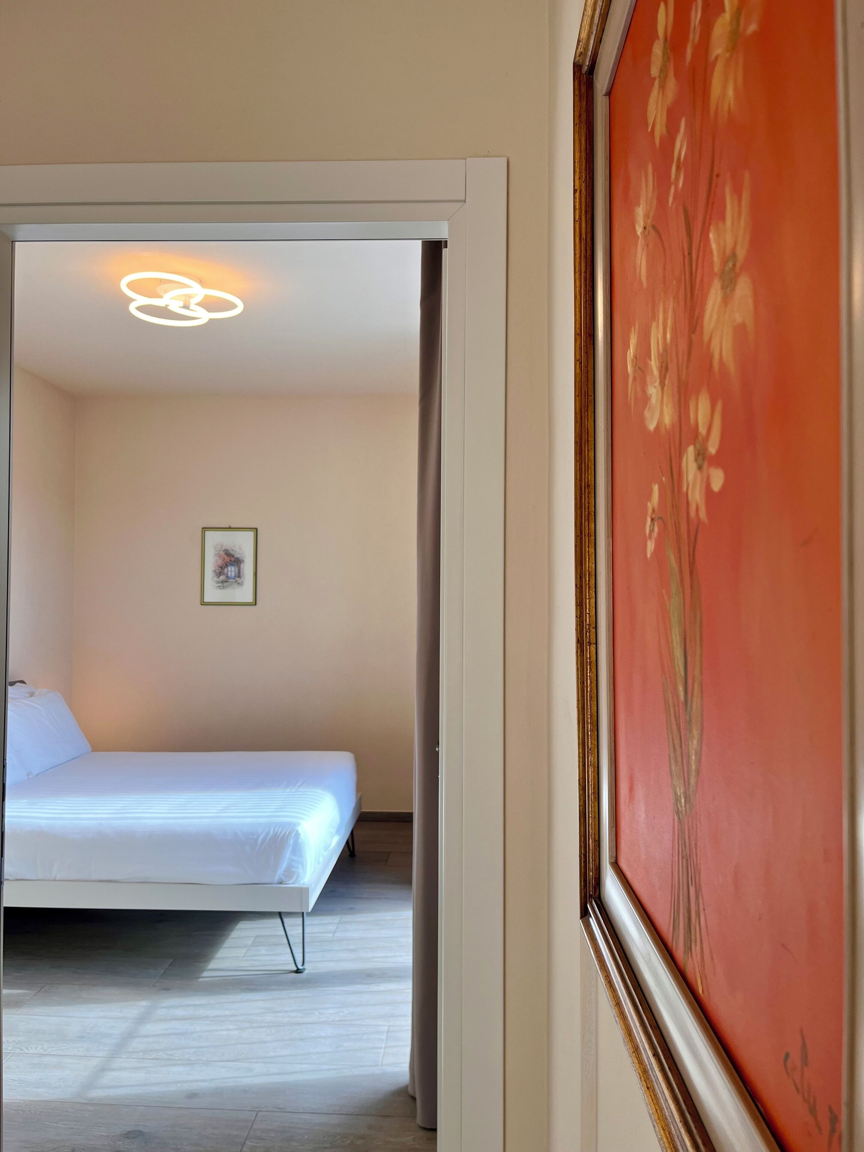 A bedroom with a bed, a framed picture on the wall, and a ceiling light fixture.
