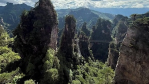 A mountainous landscape with prominent rock formations and dense greenery. - QīTiānYōupǐnZhāngjiājièDàyōngGǔchéngDiàn (Zhangjiajie)