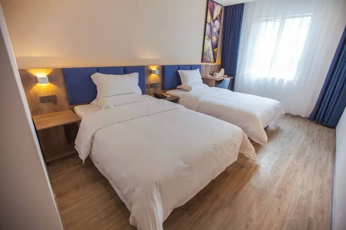 Quarto de hotel com duas camas, soalho em madeira e um quadro na parede.