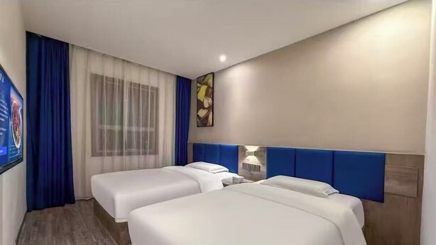 A hotel room with two beds, a TV, a window with curtains, and a painting on the wall. - QīTiānYōupǐnZhāngjiājièDàyōngGǔchéngDiàn (Zhangjiajie)
