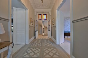A hallway with a patterned floor, white doors, and a staircase leading to a room with a bed. - Villa Monplaisir – Pool, Billiards, Peaceful (Avignon)