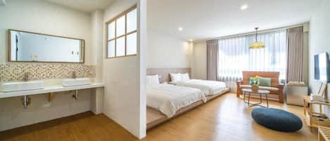 A modern hotel room with a large bed, a sofa, a small table, and a TV.