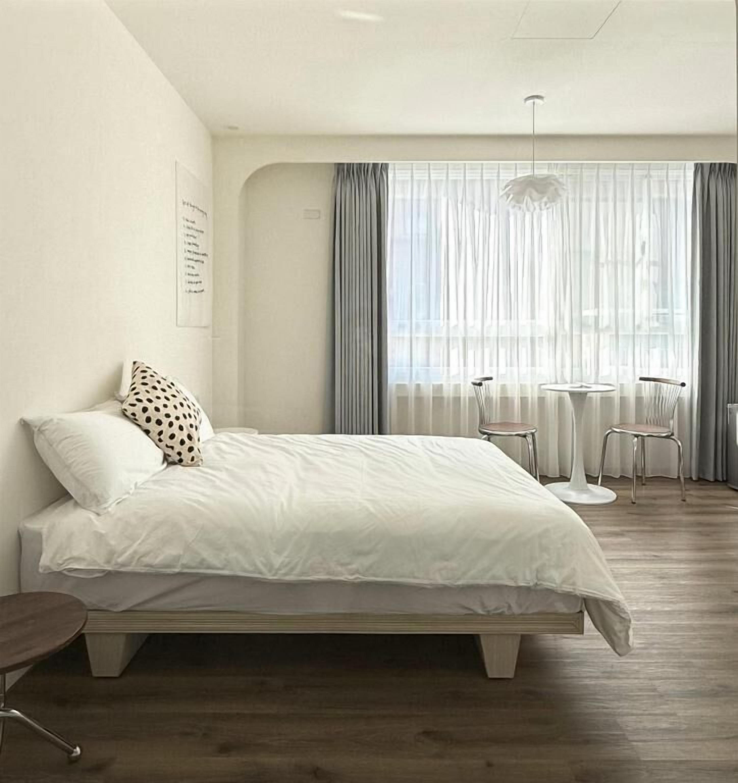 A modern bedroom with a bed, a small table, and chairs.