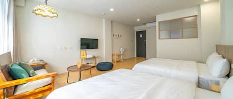 Ein Hotelzimmer mit zwei Betten, einem Fernseher, einem Schreibtisch mit Stuhl und einem Fenster.