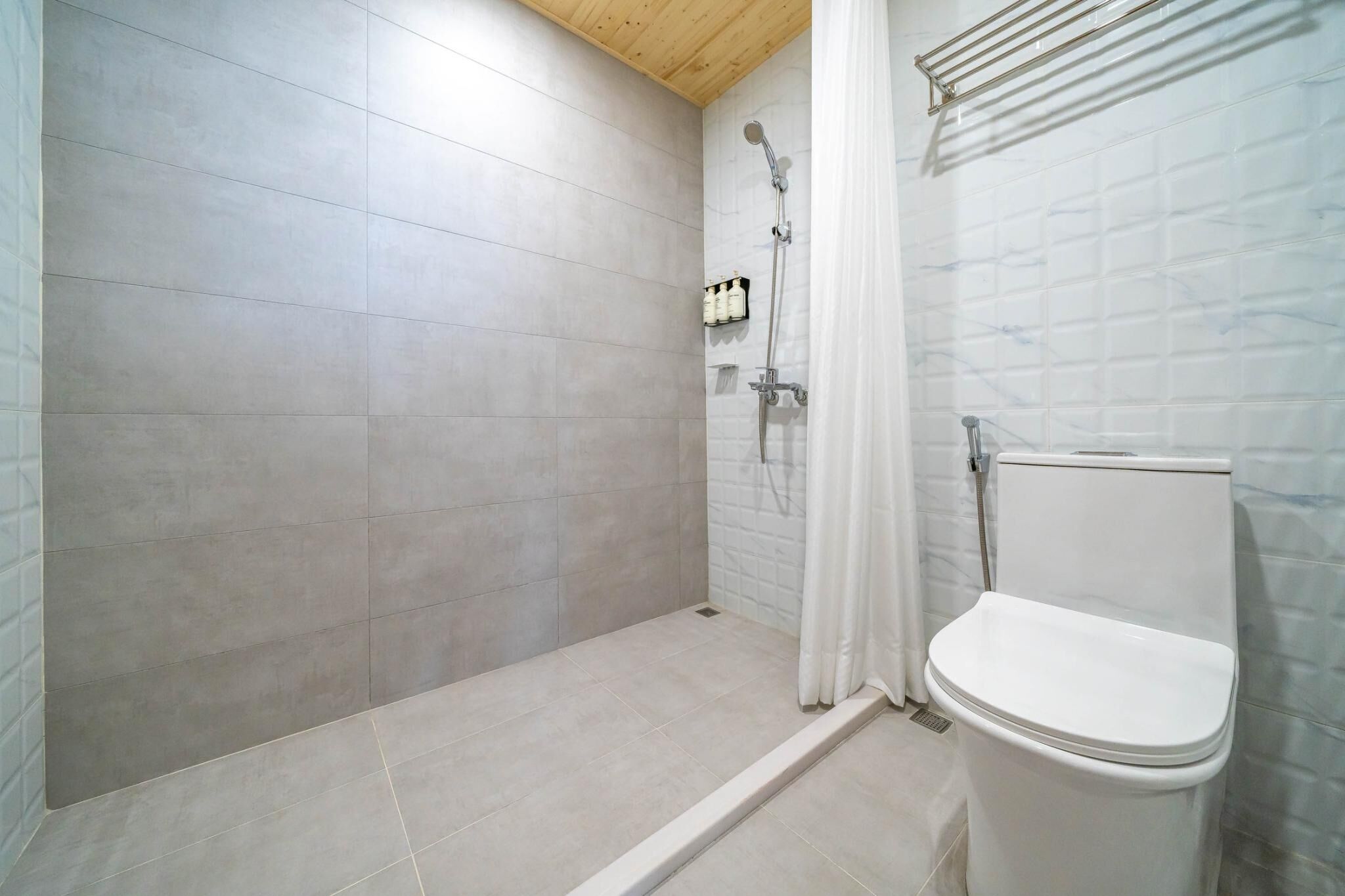 A bathroom with a shower, toilet, and tiled walls.