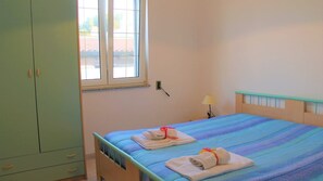 A bedroom with a bed, a wardrobe, a window, and a lamp. - Quadrilocale Angela N°6 - Salento Reservation (Torre Suda)