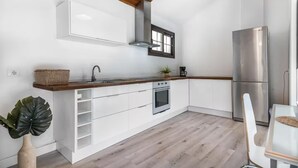 Een moderne keuken met witte kastjes, een roestvrijstalen koelkast en een houten plafond.
