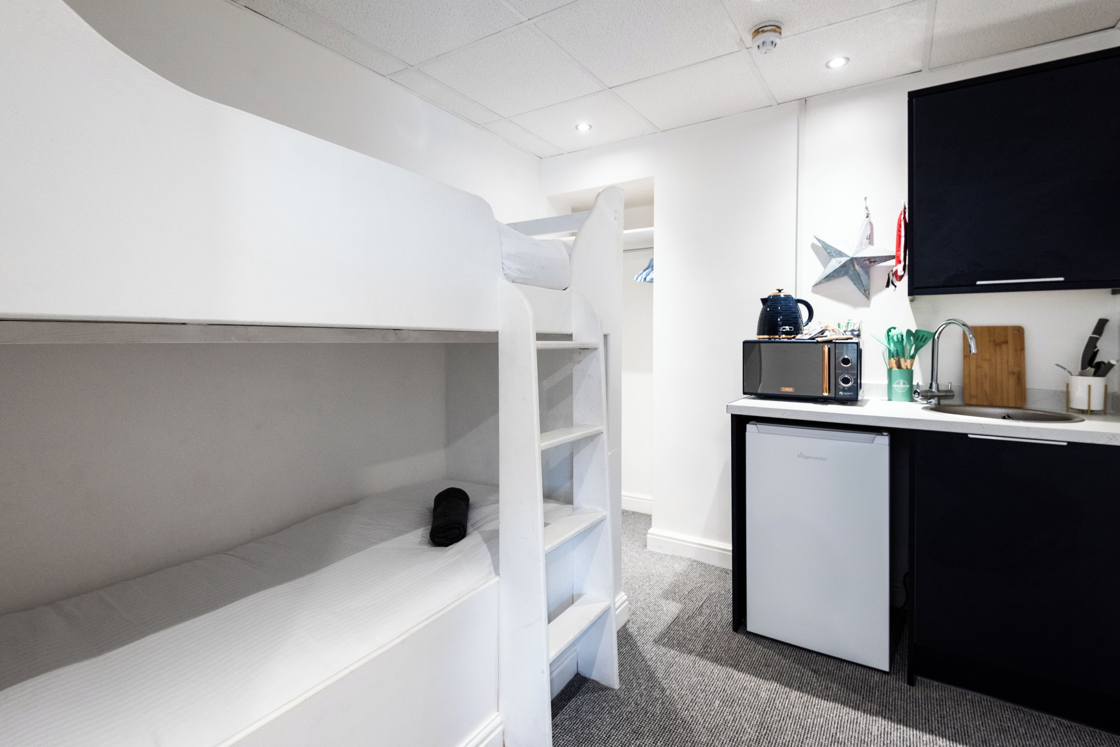 A modern kitchen with white cabinetry, a microwave, and a small refrigerator.