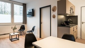Ett modernt kök med en inbyggd ugn, en matplats med bord och stolar samt en tv som är monterad på väggen.