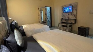 Hotellihuone, jossa on kaksi sänkyä, kattotuuletin, televisio ja marmorinen takka.