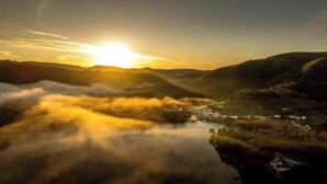 A landscape with a body of water, hills, and a sunrise.