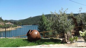 A large ceramic pot, a fenced area, and a body of water with hills in the background.