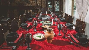 A long dining table set with multiple plates, glasses, and cutlery, surrounded by chairs.