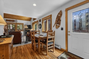 A cozy room with a wooden dining table, chairs, a television, and a fireplace. - Riverfront Condo • Fireplace • Close to RMNP (Estes Park)