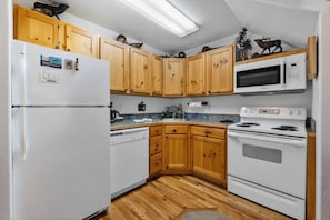 Una cocina compacta con armarios de madera, un refrigerador blanco, un microondas y una estufa.