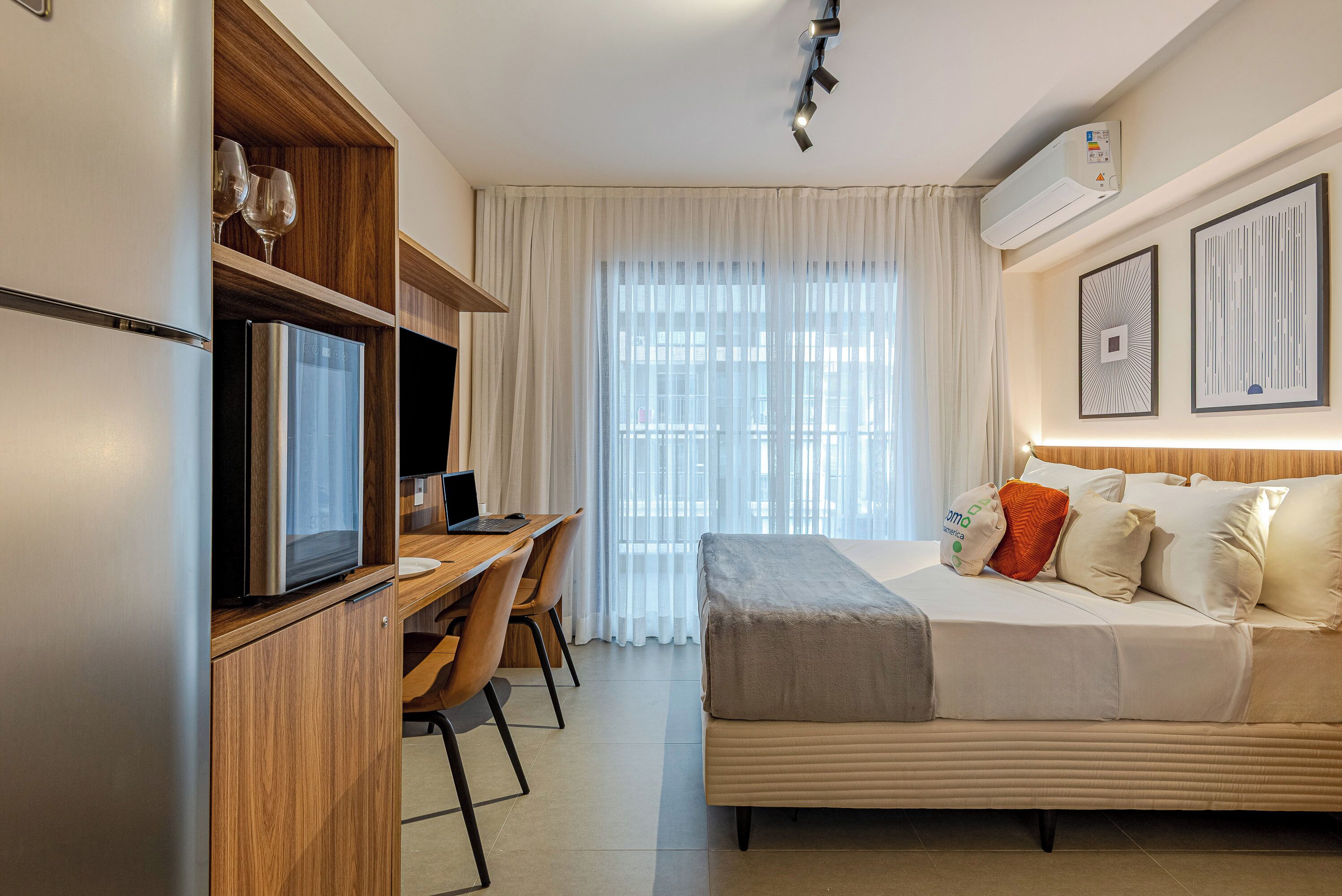Una camera d'albergo moderna con un letto, una scrivania e una TV integrata.