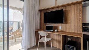 Ein modernes Zimmer mit einem Holztisch, einem Flachbildfernseher, einem Laptop, einem weißen Stuhl und einer Kaffeetasse.
