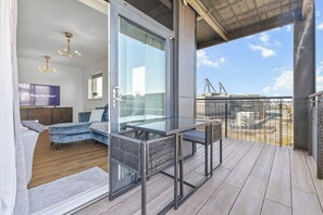 Una habitación moderna con una puerta de cristal que da a un balcón, un sofá, una mesa y una pantalla de televisión que muestra 'Pass the Keys'.