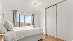 Ein Schlafzimmer mit Bett, Fenster, Kleiderschrank und Deckenleuchte.