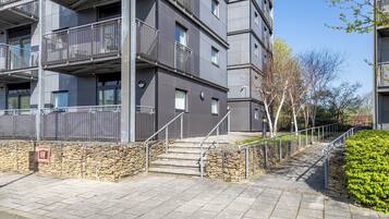 A multi-story building with balconies, stone walls, and a paved walkway.