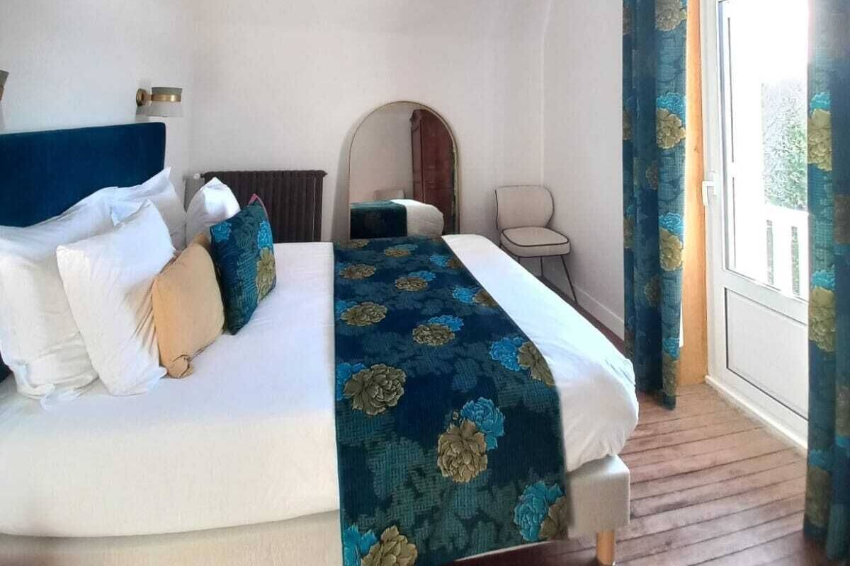Habitación de hotel con una cama grande, una silla, una mesita y vistas a través de una puerta.