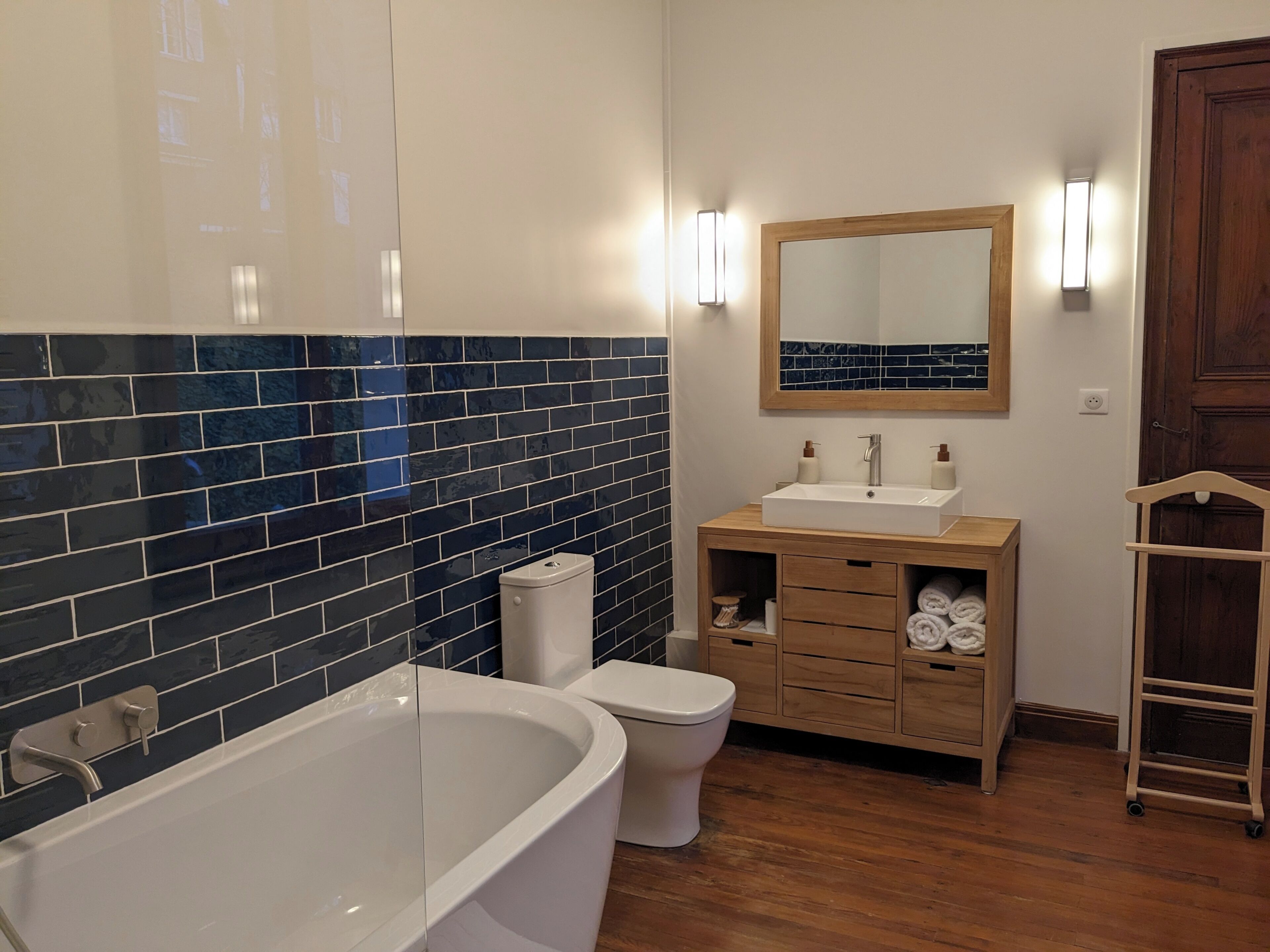 Een badkamer met een bad, toilet, wastafel en een houten kast.