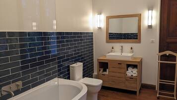 Een badkamer met een bad, toilet, wastafel en een houten kast.