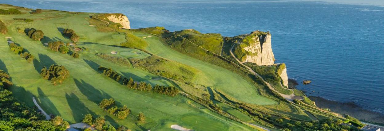 Un campo de golf costero con un acantilado destacado y vista al océano.