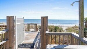 Eine Holzterrasse führt zu einem Strand mit freiem Blick auf den Ozean.