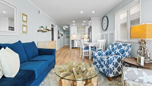 Ein modernes Wohnzimmer mit einem blauen Sofa, einem Glastisch und einem gemusterten Sessel.