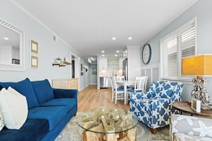 Ein modernes Wohnzimmer mit einem blauen Sofa, einem Glastisch und einem gemusterten Sessel.