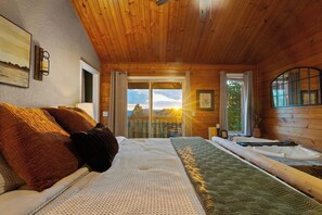 A wooden cabin bedroom with a bed, a window with curtains, a view of the outside, and a bathtub. - Epic Views•Hot Tub•Game Room•Private•Near PF, Gatlinburg & GSMNP (Sevierville)