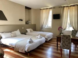 Habitación de hotel con dos camas, un escritorio, una silla, un televisor y una ventana con cortinas.