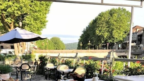 An outdoor café with tables, chairs, and umbrellas.