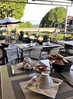 Un café al aire libre con mesas, sillas y sombrillas.
