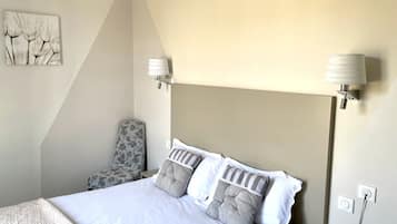 Een hotelkamer met een bed, een stoel, een lamp en een schilderij aan de muur.