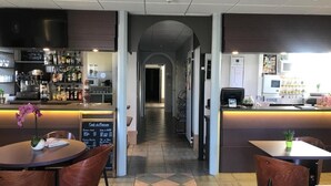 A restaurant with a bar area, a counter, and a seating area with tables and chairs.